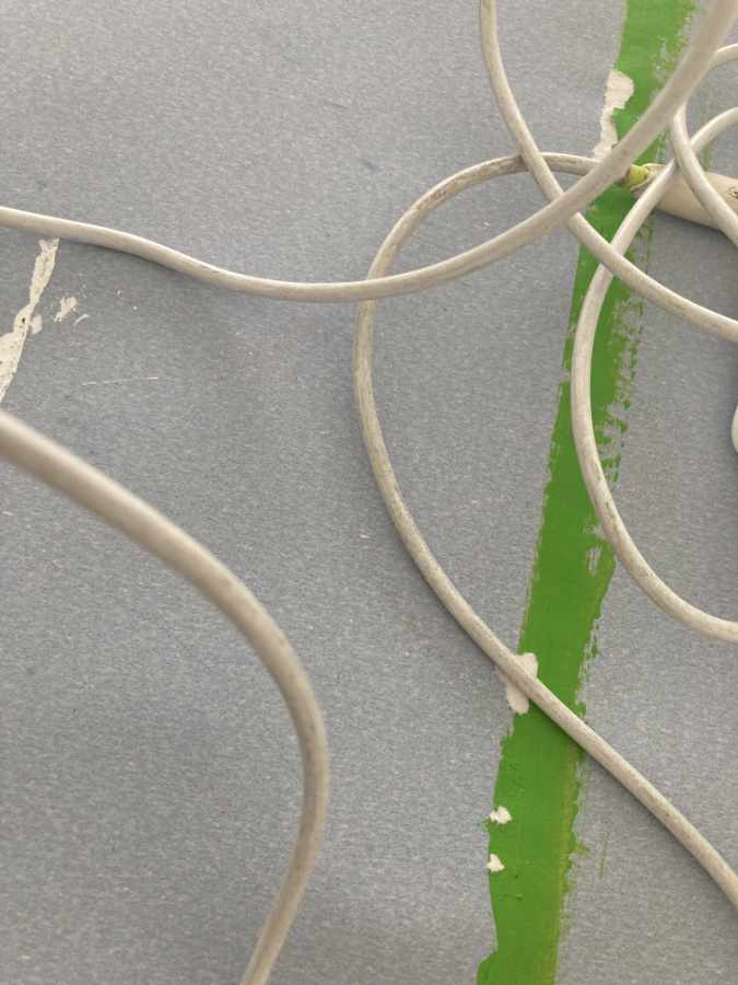 Ein hellblauer Untergrund, darauf ist ein leuchtender grüner Strich gemalt. Darüber liegt ein verdrehtes weißes Kabel.