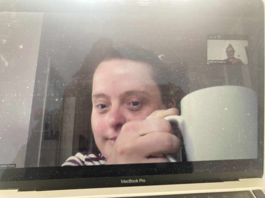 Eine lächelnde Frau blickt in die Kamera. Sie hält einen großen weißen Kaffeebecher in der Hand.