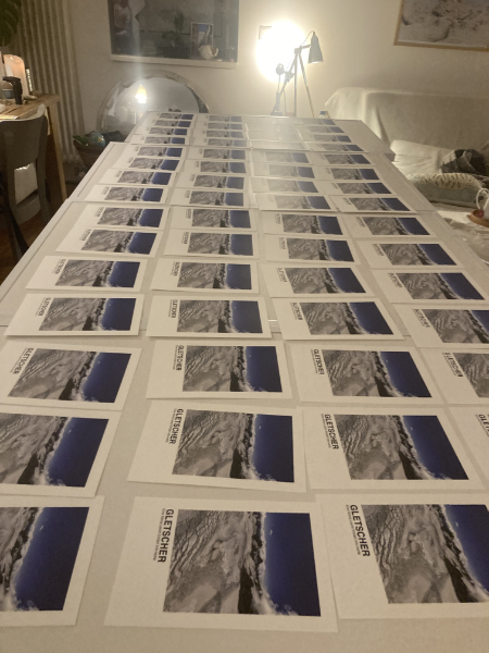 Auf dem Foto sieht man ganz viele Karten nebeneinander gelegt. Auf den Karten ist ein Foto von einem Gletscher abgebildet.