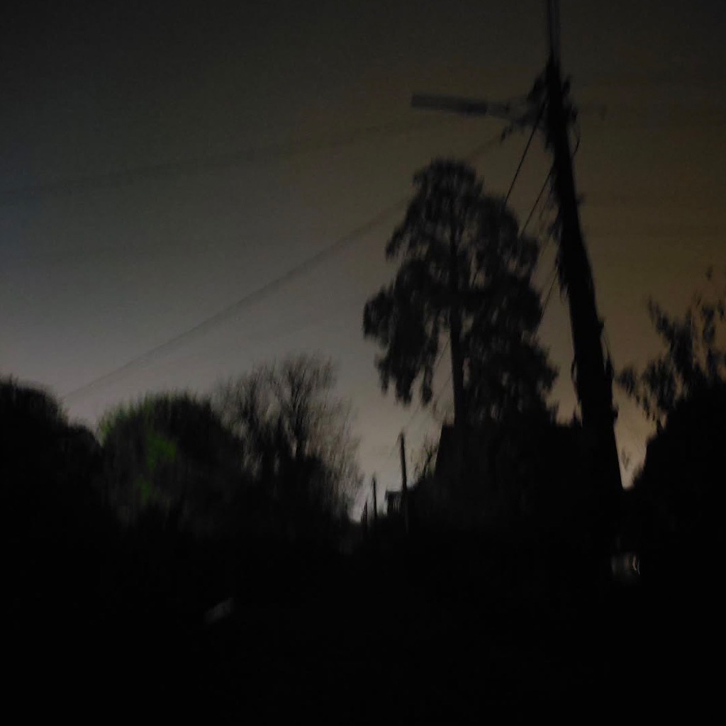 Auf dem Foto sieht man einen Stommast an dem eine Straßenlampe befestigt ist. Die Lampe ist aus und die Straße ist sehr dunkel.
